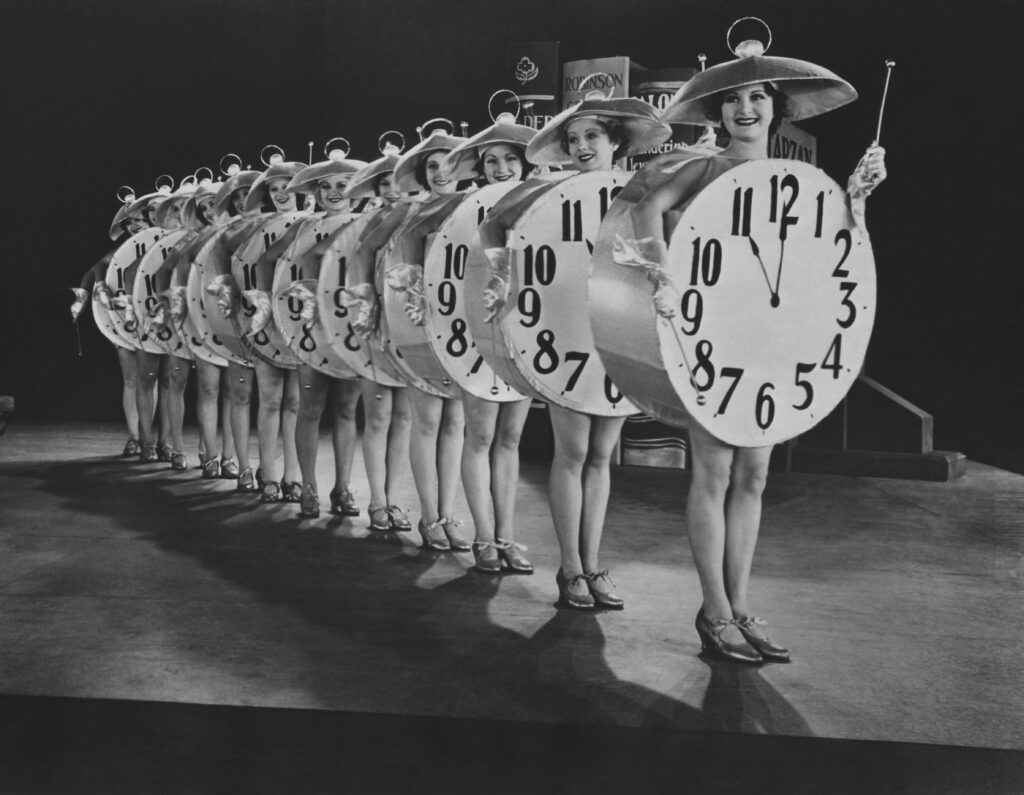 Women dressed as clocks. They are about to tap dance. It is amazing.