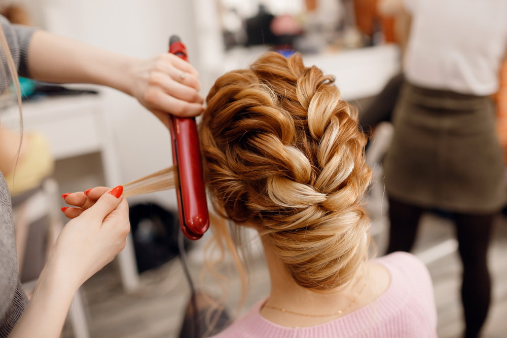 a cosmetology student does the hair of a woman for an event