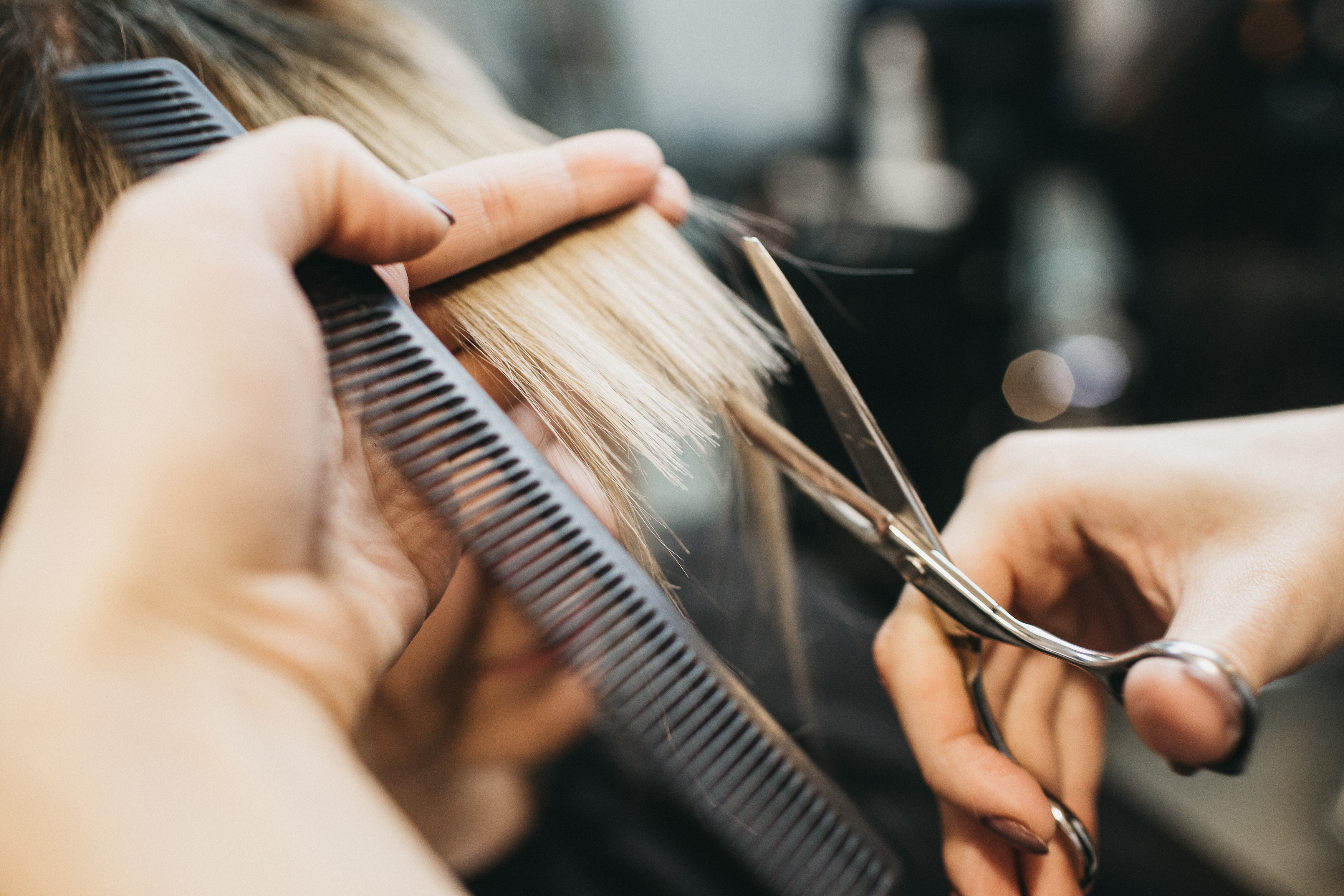 up close of hairstylist's hands cutting ends of client's hair