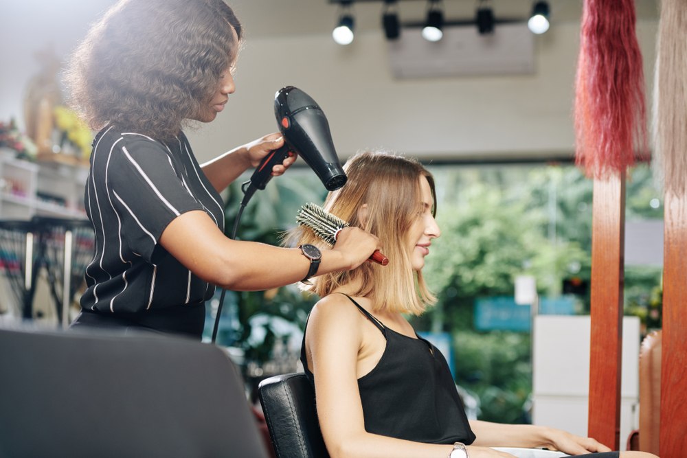 cosmetologist blowdrying clients hair