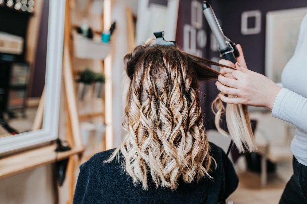 cosmetologist curling clients hair